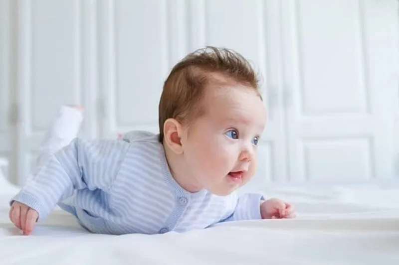 Khi nằm sấp, bé có thể tự nâng đầu và ngực vững vàng nhờ cơ cổ đã củng cố hơn.